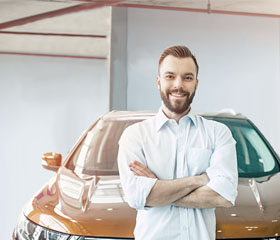 Hombre sonriendo con su coche detrás